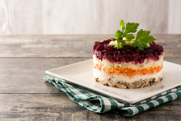 Traditional Russian herring salad with beetroot and carrots on wooden table. Copy space	