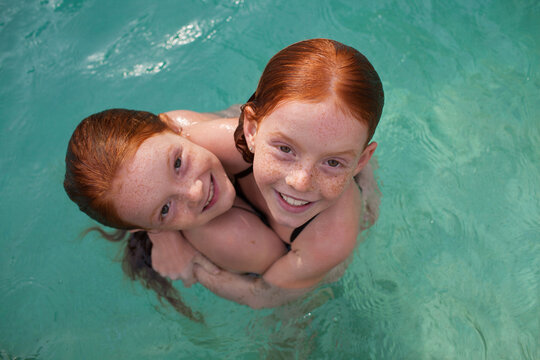Two girls hugging in a backyard swimming pool