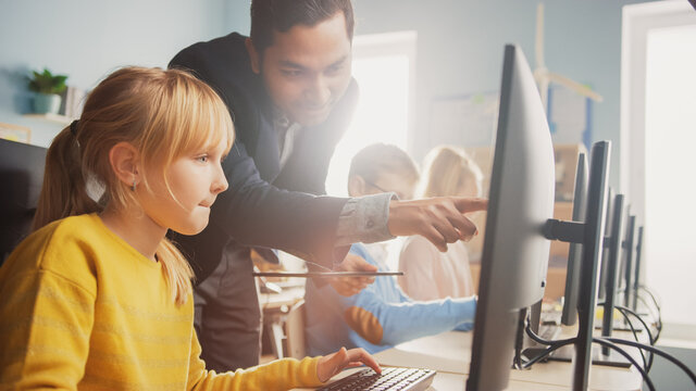 Elementary School Science Classroom: Teacher Explains to a Smart Little Schoolgirl how to use Personal Computer, to Learn Programming Language needed for Software Coding. Modern Education in Progress - Powered by Adobe