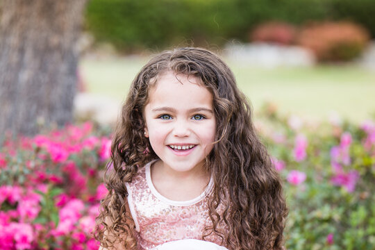 Young girl mixed race aboriginal and caucasian sitting in garden with flowers smiling