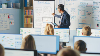 Elementary School Class: Teacher Uses Interactive Digital Whiteboard, Explains Lesson to Diverse...