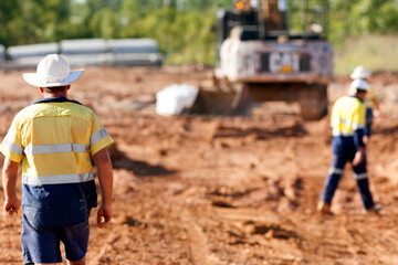 Industrial workers on a building site with heavy machinery in the background