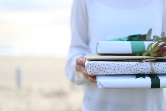 Woman holding presents with beach in background