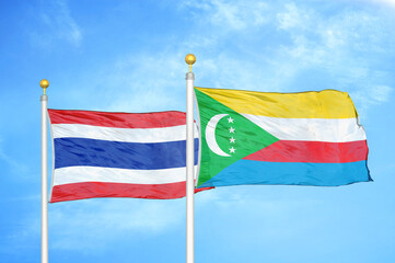 Thailand and Comoros two flags on flagpoles and blue sky
