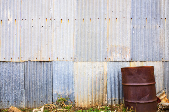 Rusty drum in front of corrugated iron wall - horizontal