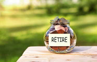 Retire. Glass jar with coins, on a wooden table, on a natural background.Investment and finance concept.