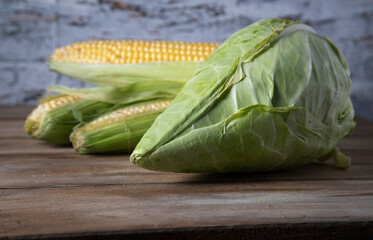 
Fresh white cabbage and corn on a wooden table