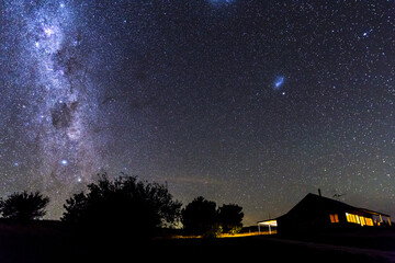 Cottage at night with lights in windows and starry sky