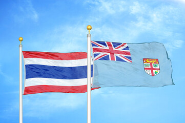 Thailand and Fiji two flags on flagpoles and blue sky