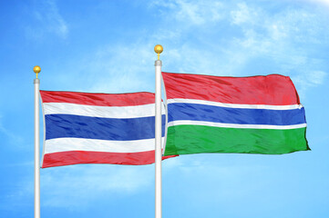 Thailand and Gambia two flags on flagpoles and blue sky