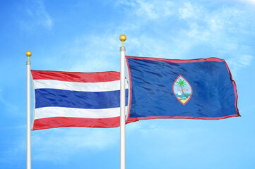 Thailand and Guam two flags on flagpoles and blue sky
