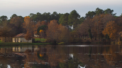 Obraz premium Lac paisible en automne, avec vue sur une maison abandonnée