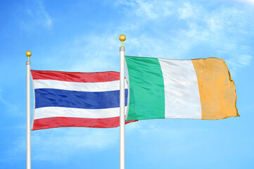 Thailand and Ireland two flags on flagpoles and blue sky