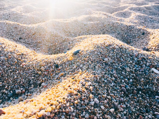 Sand beach texture background with rays of the sun. Detail of the grains of coarse sand.