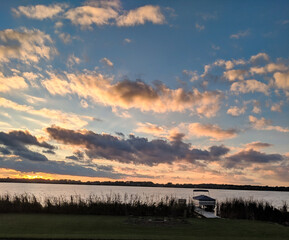 sunset on the lake with silohuette of boat parked at waters edge.
