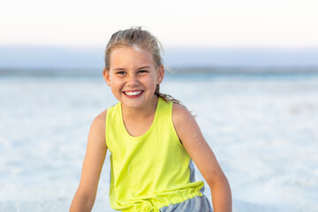 young girl with hair tied back in fluoro top on the beach