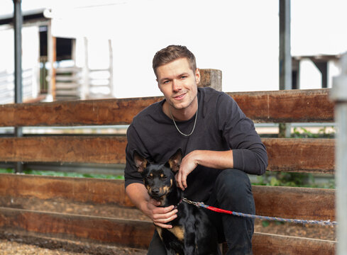 Young man in black with a kelpie dog