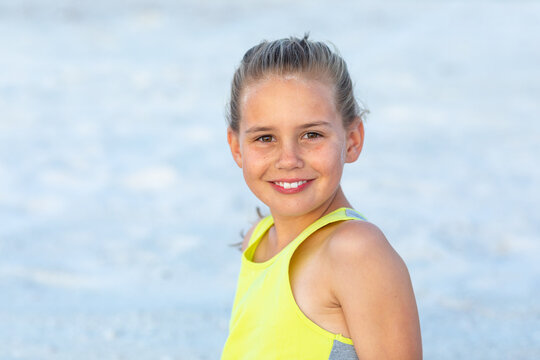 young girl with hair tied back in fluoro top on the beach