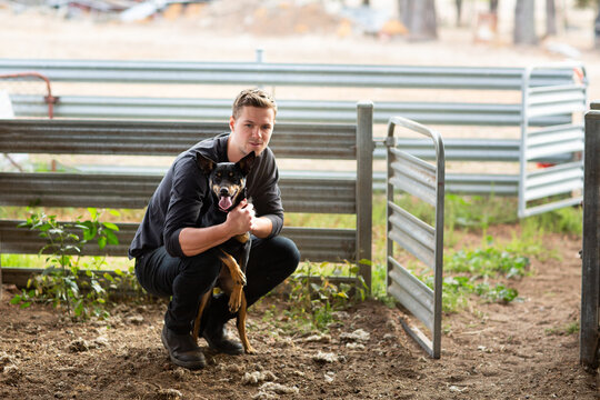 Young man in black with kelpie dog
