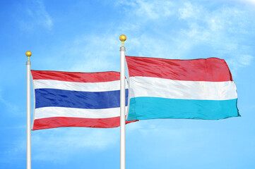 Thailand and Luxembourg two flags on flagpoles and blue sky