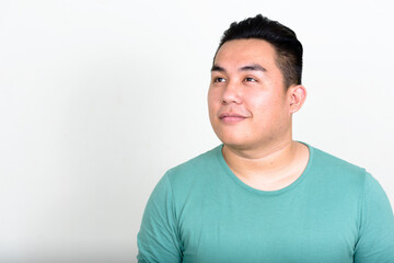 Portrait of young handsome overweight Asian man thinking