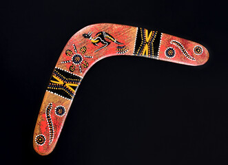 Australian hand painted boomerang stock images. Boomerang isolated on a black background with copy space for text. Boomerang frame stock images - obrazy, fototapety, plakaty