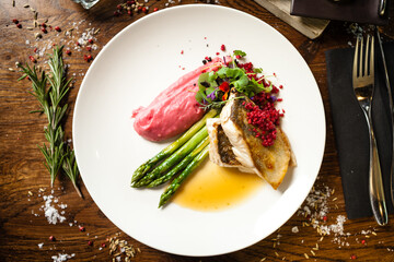 Pike-perch fillet. Asparagus, pearl couscous, white wine sauce, beet-flavored mashed potatoes. Delicious seafood fish closeup served on a table for lunch in modern cuisine gourmet restaurant