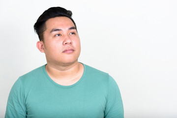 Portrait of young handsome overweight Asian man thinking