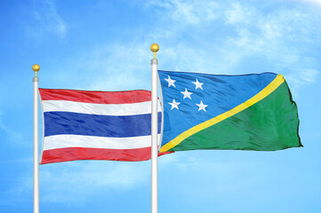 Thailand and Solomon Islands two flags on flagpoles and blue sky