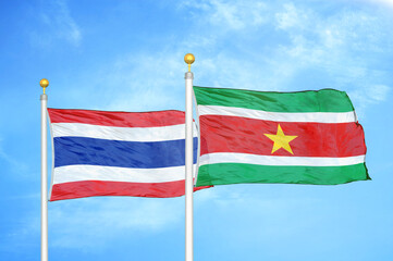 Thailand and Suriname two flags on flagpoles and blue sky