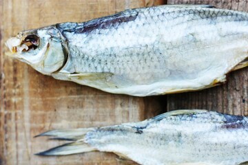Two dried fish on a wooden background 