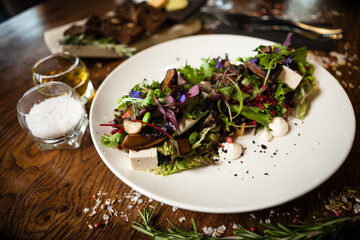 Fresh vegan salad. Avocado, couscous, melon, portobello, soybean, tofu on white plate. Delicious healthy mixed greens food closeup served on a table for lunch in modern cuisine gourmet restaurant.