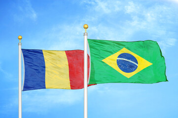 Romania and Brazil two flags on flagpoles and blue sky