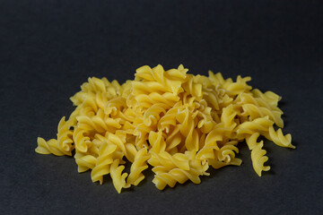Pasta on a black background. The pasta is in a heap in the middle of the frame. Cooking concept