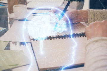 Double exposure of writing hand on background with brain hologram. Concept of learning.
