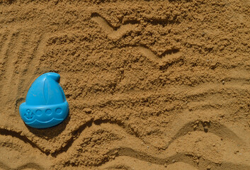 Fototapeta na wymiar Children's sand mold in the shape of a boat. The drawing in the sand is the sea.