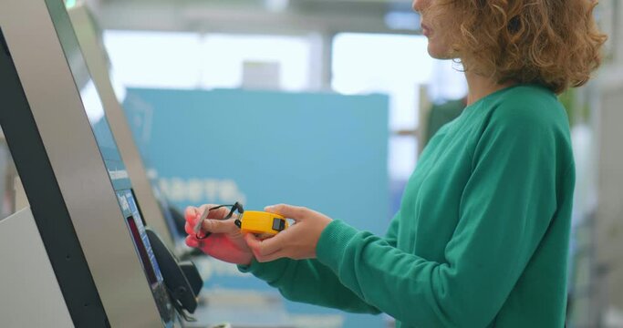 Young woman scanning measuring tape shopping in diy store and buying at self-checkout