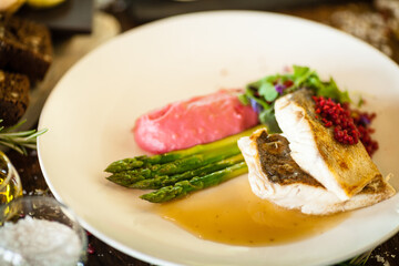 Pike-perch fillet. Asparagus, pearl couscous, white wine sauce, beet-flavored mashed potatoes. Delicious seafood fish closeup served on a table for lunch in modern cuisine gourmet restaurant