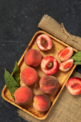 juicy ripe peach fruits on a wooden platter, on a dark background. agricultural products, the concept of the harvest season.