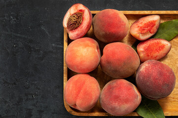 juicy ripe peach fruits on a wooden platter, on a dark background. agricultural products, the concept of the harvest season.