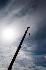 Crane boom with hook
on cloudy sky.