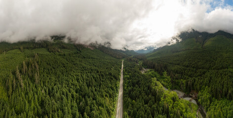 Aerial panoramic View of a scenic Highway surrounded by Canadian Mountain Landscape during a summer morning. Taken in Northern Vancouver Island, British Columbia, Canada.