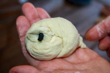 A yeast dough bird lies on the chef's hand