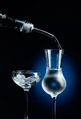 Vodka is poured from bottle into glass with ice.