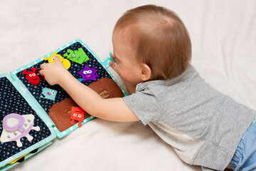 Child plays with a felt handmade book. Concept of early development for child