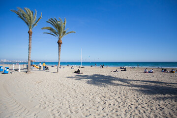 Fototapeta na wymiar Palm trees and people at the beach in Spain