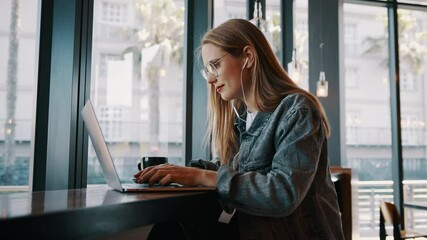 Young woman working on laptop computer at a cafe. Caucasian female influencer in a coffee shop using a laptop.
 - Powered by Adobe