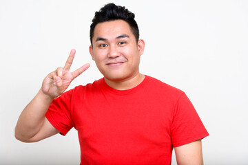 Portrait of young overweight Asian man with peace sign