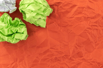 Two salad sheets of crumpled paper and one sheet of crumpled white paper lie on mint red paper