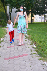 Mother and child wear facemask during coronavirus, flu outbreak. Child and mom in medical mask on a walk.